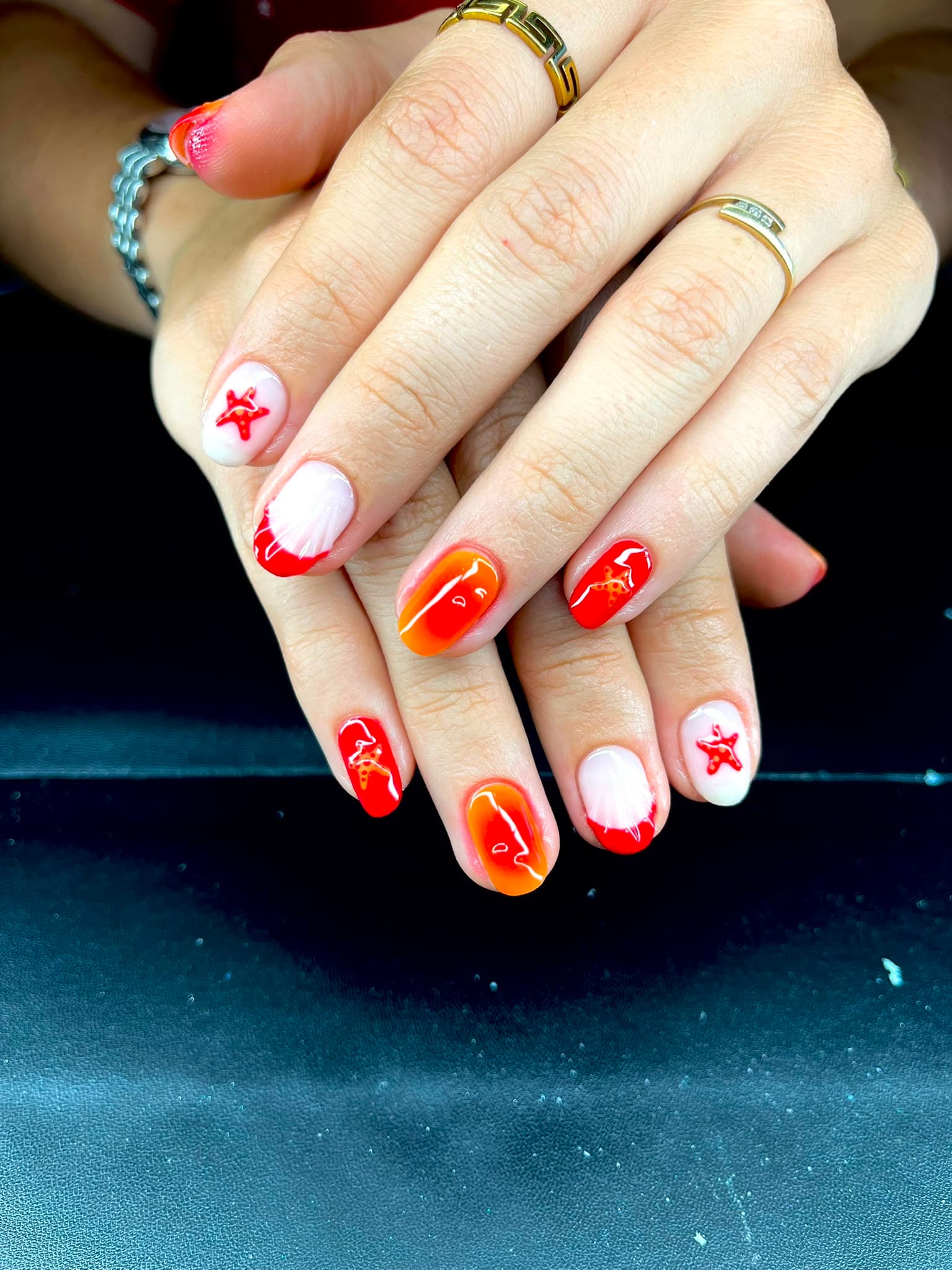 Nail art rouge orange avec étoiles de mer et coquillages